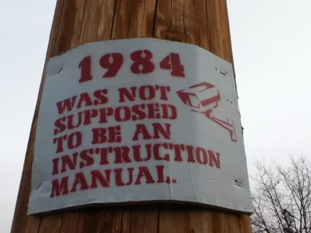 Schild mit dem Bild einer Überwachungsakamera und der Aufschrift "1984 was not supposed an instruction manual" 